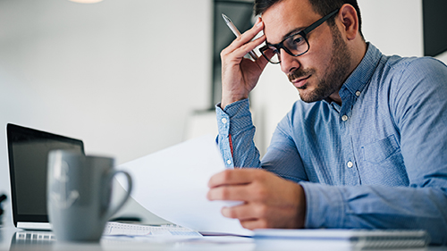 Man pondering over paper documents