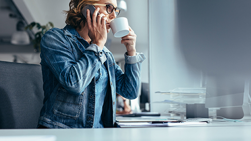 Young businesswoman making phone call and having coffee Employee drinking coffee
