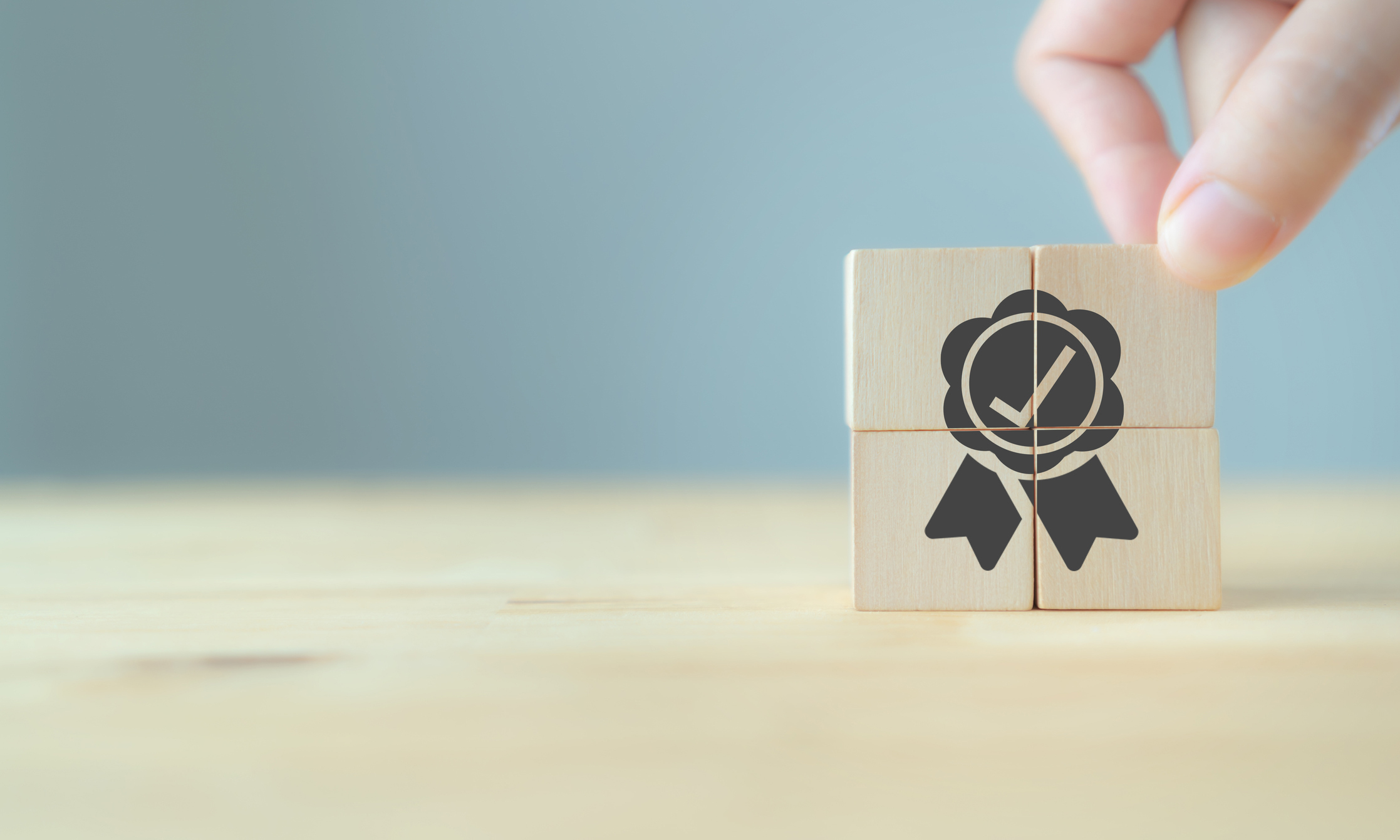 Quality warranty concept. Man's hand puts the wooden cubes with quality warranty icon on wooden cubes with grey background. Used for banner and advertising product and service quality commitment. eVoucher ClaimShop